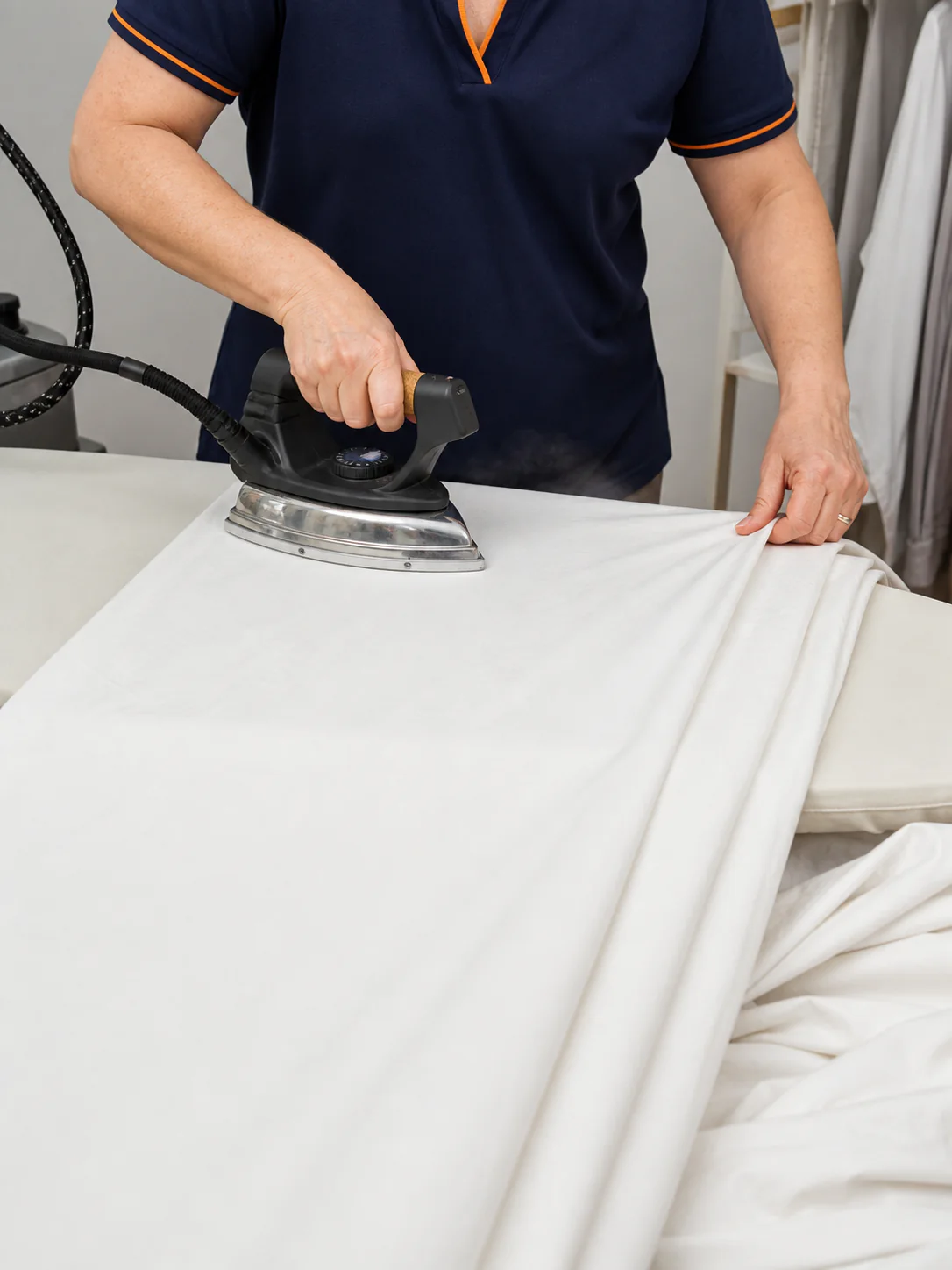 A double duvet cover being pressed in sections on a wide ironing board